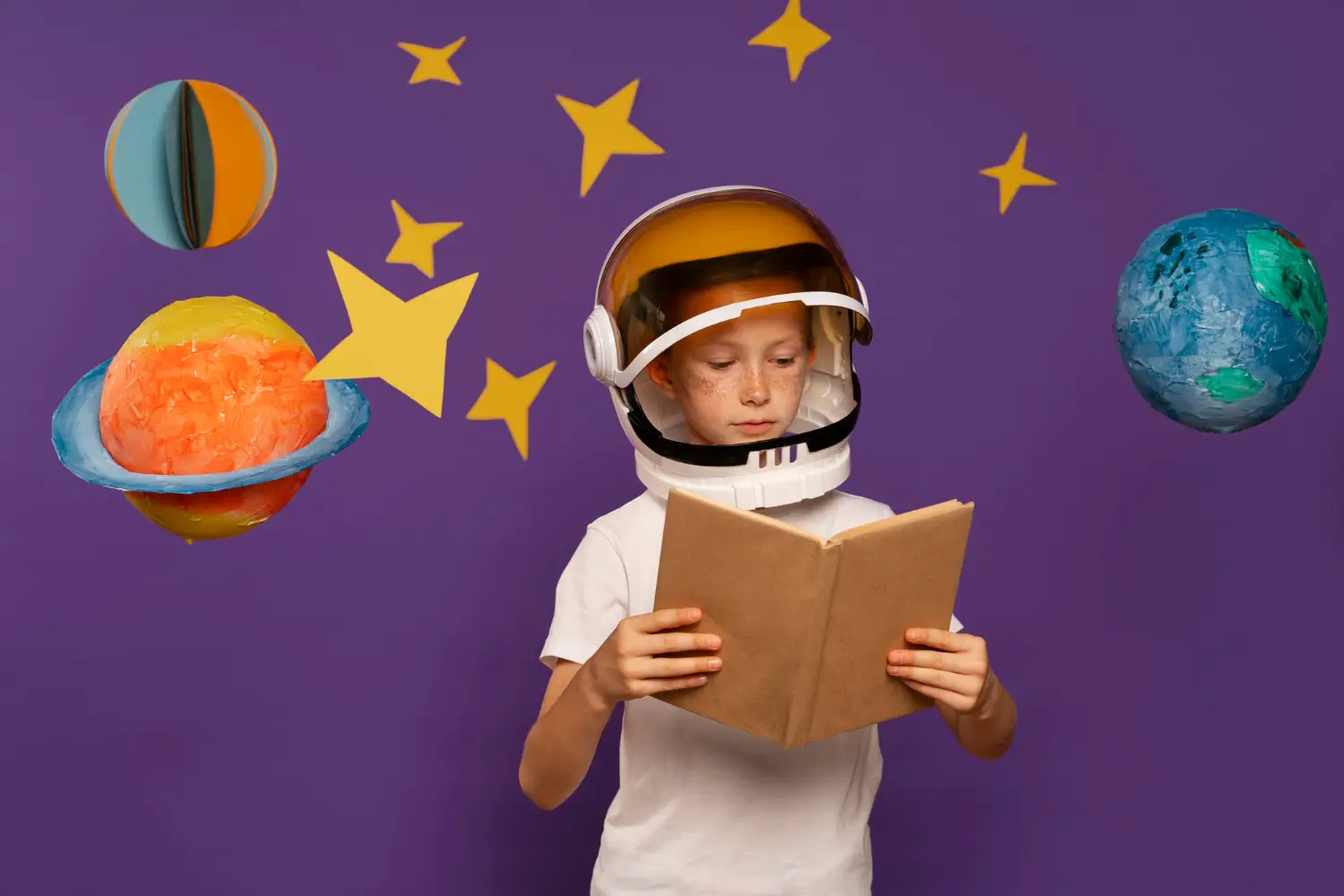 Imaginação e Processos de criação na clínica histórico-cultural. Foto de uma criança com capacete de astronauta, num fundo roxo, lendo um livro e vários planetas e estrelas ao redor dele. Na clínica histórico-cultural de Vigotski, o processo terapêutico visa transformar modos de existir por meio da criação simbólica. A criatividade, fundamentada na imaginação, surge da tensão entre o que é e o que poderia ser, impulsionando a reinvenção diante do sofrimento. O sofrimento é visto como expressão da relação do sujeito com sua história social e simbólica, e a terapia abre espaço para novas representações que possibilitam mudanças internas. Assim, a clínica oferece a chance de ressignificar experiências e recriar-se como agente da própria vida.